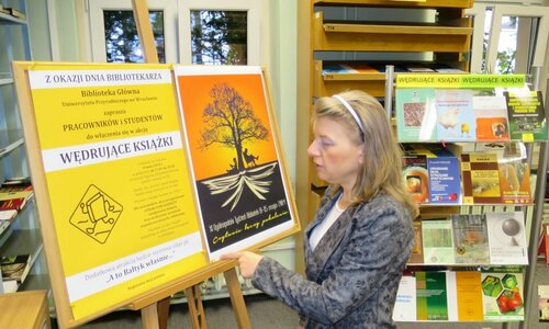 Kobieta wskazująca na plakat z okazji Dnia Bibliotekarza.